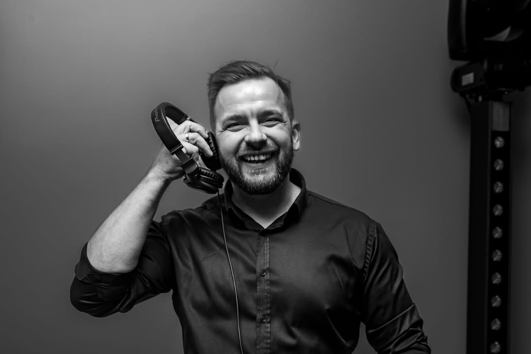 dj-ogi-czarno-biale-portret-ze-sluchawkami.jpg Klasyczny portret DJ-a ze słuchawkami w dłoni — naturalny uśmiech